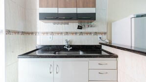Una cocina con encimera negra, armarios blancos y pileta de acero inoxidable.
