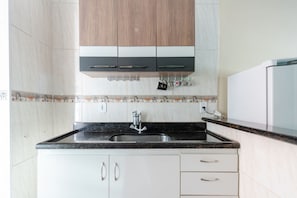 A kitchen with a black countertop, white cabinets, and a stainless steel sink. - Apto com Garagem a 550 Metros da Praia do Centro (Rio das Ostras)