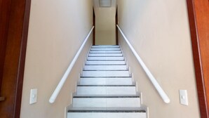Una escalera con barandillas blancas y paredes color crema.