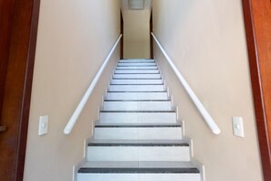 A staircase with white handrails and beige walls. - Apto com Garagem a 550 Metros da Praia do Centro (Rio das Ostras)