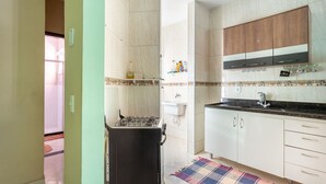 Una cocina compacta con estufa a gas, armarios blancos y un gabinete superior de madera.