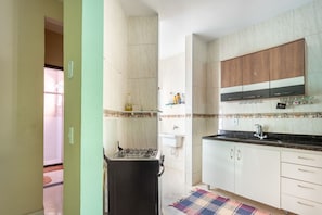 A compact kitchen with a gas stove, white cabinets, and a wooden upper cabinet. - Apto com Garagem a 550 Metros da Praia do Centro (Rio das Ostras)