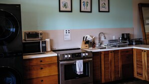 A kitchen with a washing machine, microwave, stove, sink, and wooden cabinets.