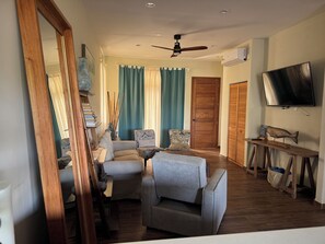 A living room with a sofa, armchairs, a TV, and a ceiling fan.