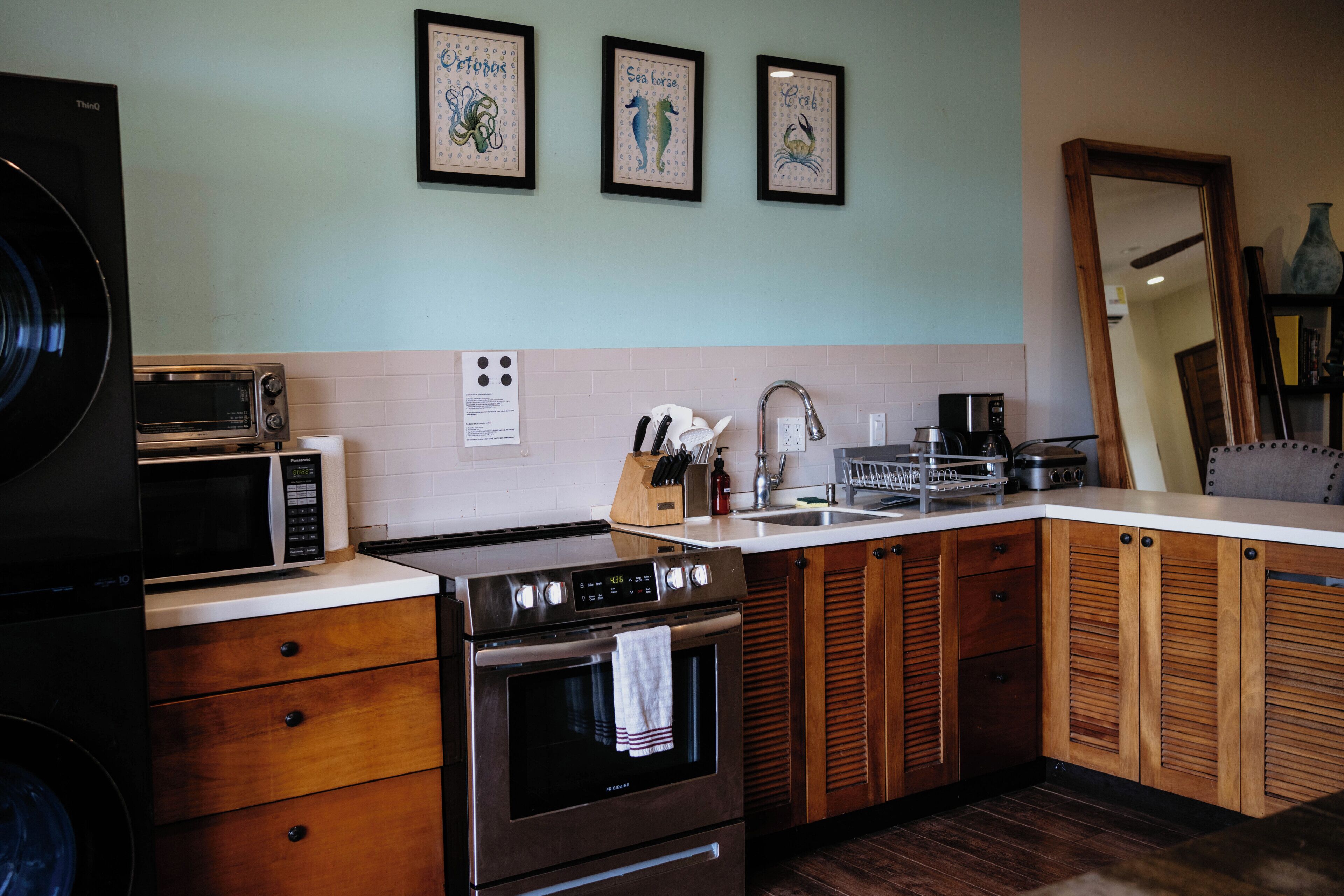 A kitchen with a stove, microwave, sink, and wooden cabinets.