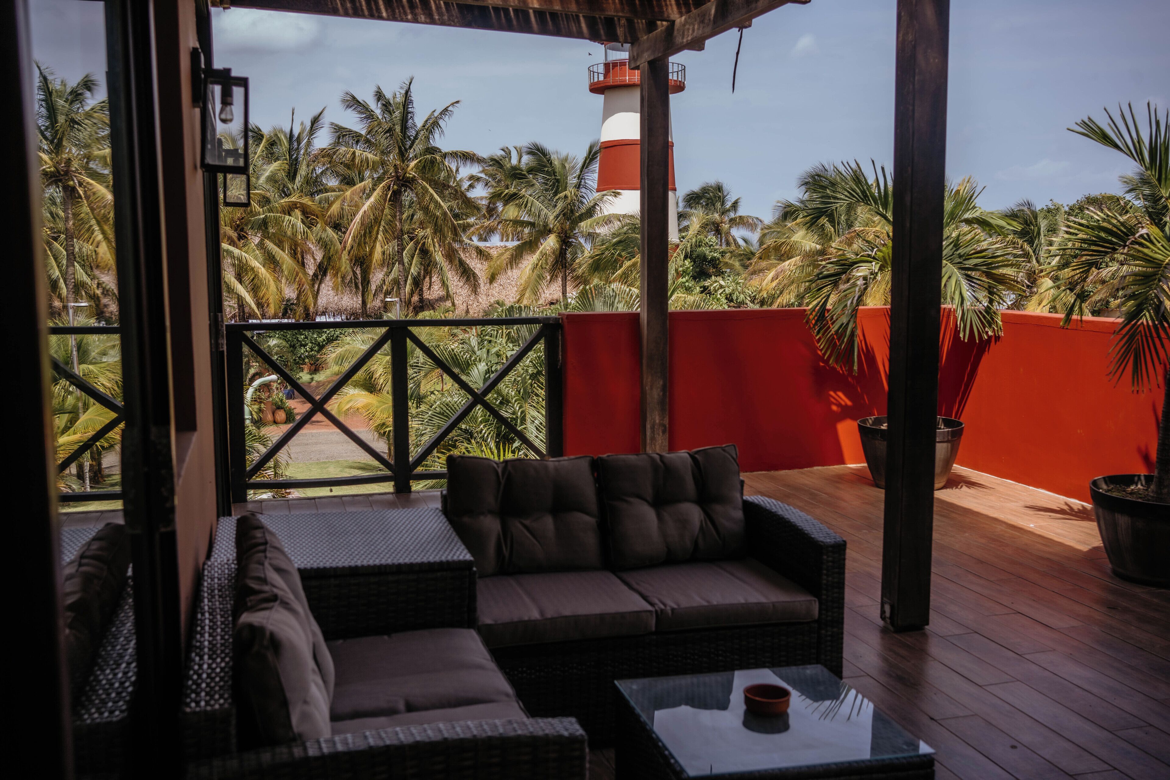 A covered outdoor seating area with a view of a lighthouse and palm trees.