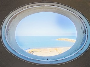 A round window with a view of a beach and calm sea. - Oblo e Ginepro sul mare by Interhome (Cecina)