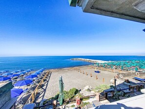 A beach with rows of blue and green umbrellas, wooden deck chairs, and a clear view of the sea. - Oblo e Ginepro sul mare by Interhome (Cecina)