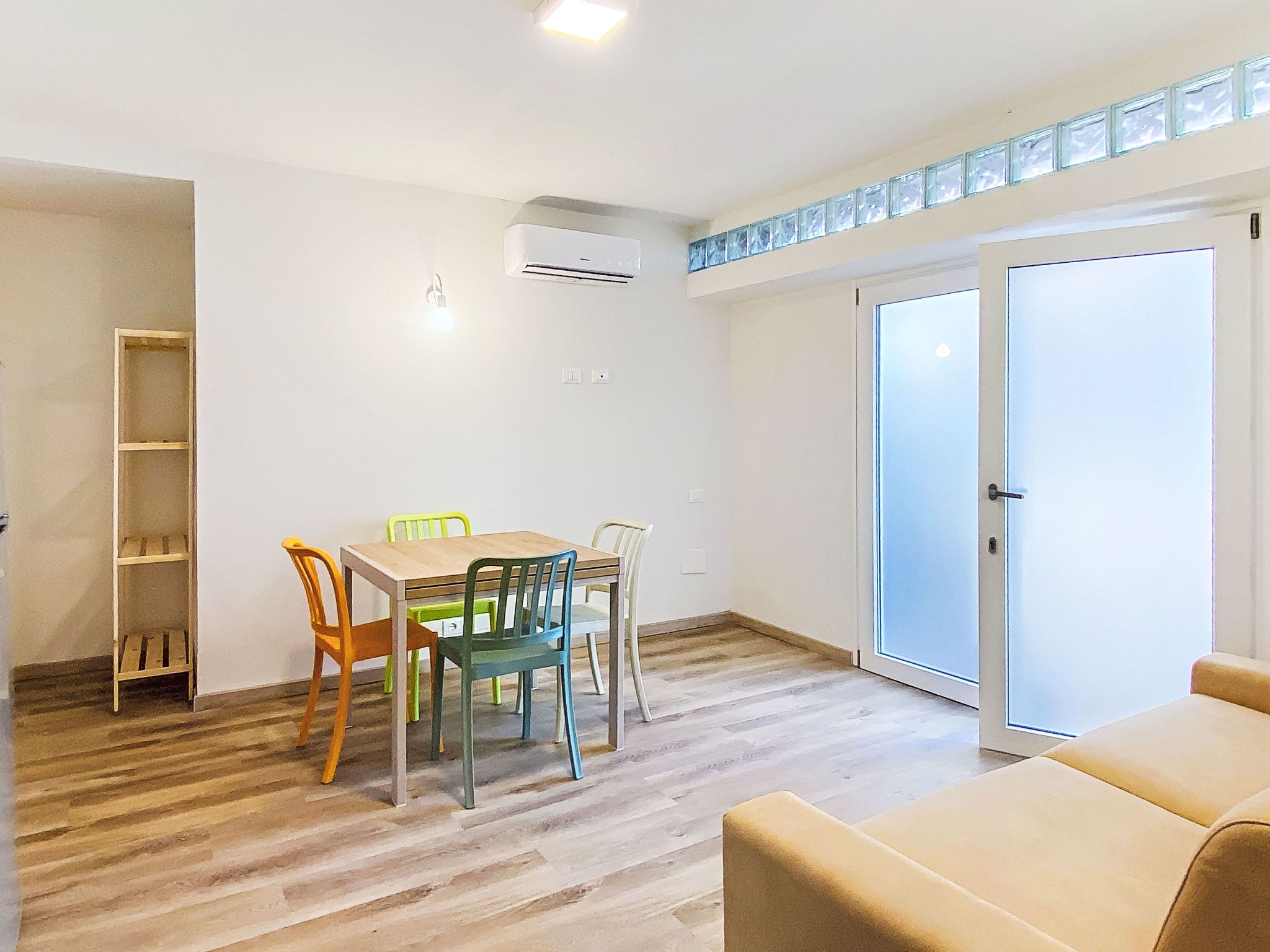Une pièce comprenant une table à manger, des chaises, un canapé, une porte-fenêtre coulissante et un appareil de climatisation.