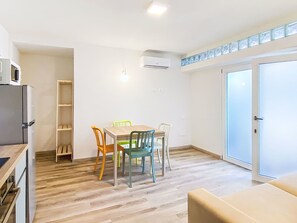 A compact kitchen with a dining area, a built-in shelf, and a sliding glass door. - Oblo e Ginepro sul mare by Interhome (Cecina)