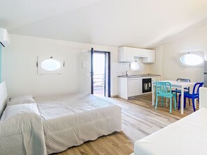 A compact room with a bed, a small kitchenette, a dining area with chairs, and a window. - Oblo sul mare by Interhome (Cecina)