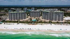 Ein Hochhaus-Hotel mit mehreren Stockwerken, ein Strand im Vordergrund und ein klarer Himmel.