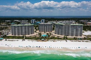 Ein Hochhaus-Hotel mit mehreren Stockwerken, ein Strand im Vordergrund und ein klarer Himmel.