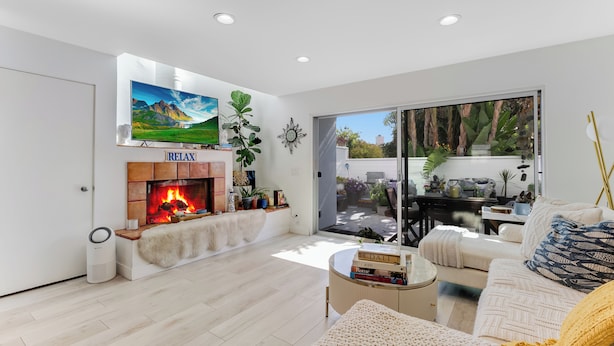 Una sala de estar moderna con chimenea, un ventanal grande y una zona de estar acogedora.