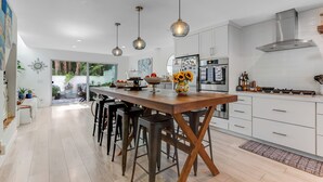 Una cocina moderna con una isla central, luces colgantes y vistas al exterior.
