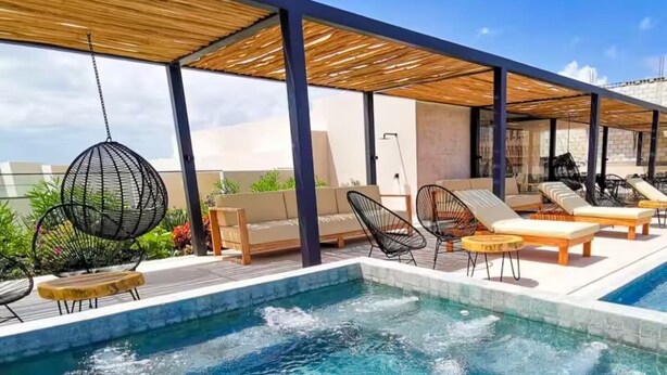 Ein Poolbereich auf dem Dach mit Liegestühlen, einer Hängematte und einer Holzpergola.