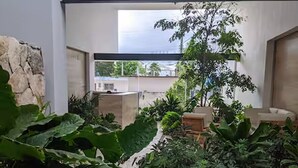 Ein moderner Innenbereich mit Garten, verschiedenen Pflanzen, einer Sitzecke und Blick ins Freie.