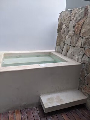 A stone wall, a rectangular bathtub, and a wooden deck. - Kaab Luxe Condo with Rooftop Pool - Beach - Parking (Playa del Carmen)