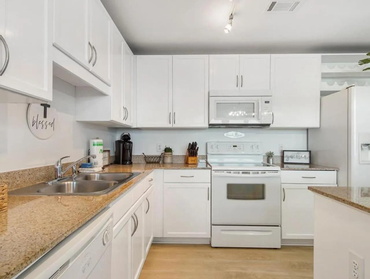 A modern kitchen with white cabinets, a granite countertop, a built-in microwave, and a stainless steel oven.