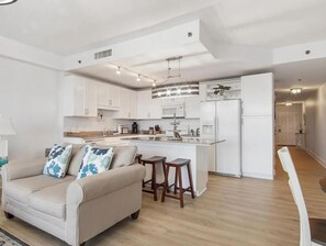 A modern kitchen with white cabinets, a central island, and a dining area with stools. - Laketown Wharf 318 (Panama City Beach)