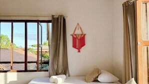 Une pièce avec un lit, une fenêtre et une décoration murale en macramé.