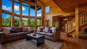 Ein geräumiges Wohnzimmer mit einem großen Ecksofa, einem Couchtisch und einer Treppe, die zu einer oberen Etage führt.