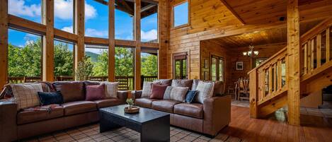 A spacious living room with a large sectional sofa, a coffee table, and a staircase leading to an upper level.