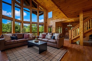 Ein geräumiges Wohnzimmer mit einem großen Ecksofa, einem Couchtisch und einer Treppe, die zu einer oberen Etage führt.