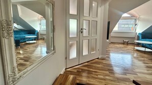 A room with a large mirror, a blue sofa, a small table, and a wooden bench. - Spacious attic duplex in a heritage building in central Sarajevo (Sarajevo)