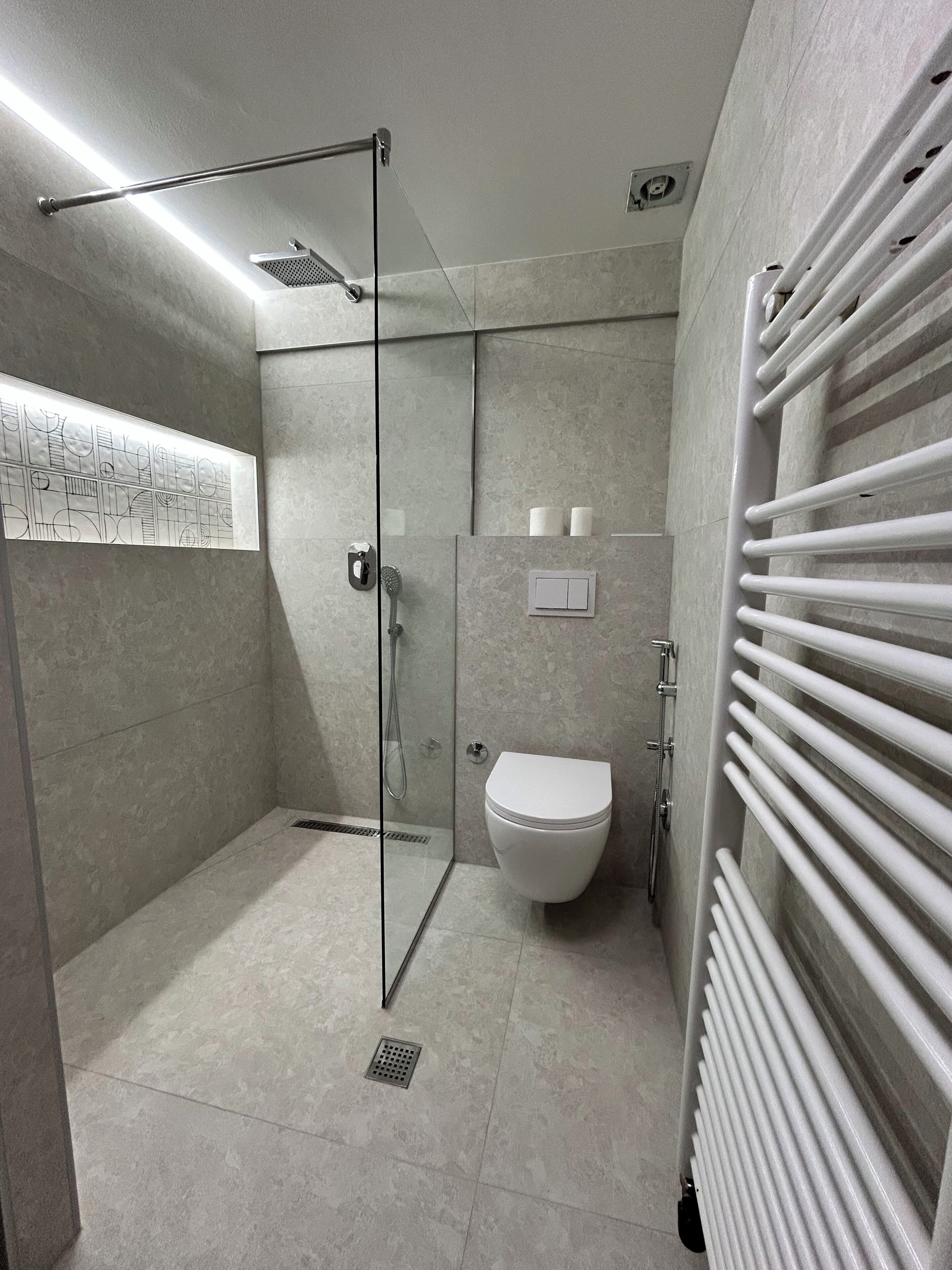 Un baño moderno con cabina de ducha de vidrio, inodoro y radiador.