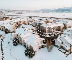 Ein Wohngebiet mit mehreren schneebedeckten Häusern, umgeben von einem Fluss und Bergen im Hintergrund.