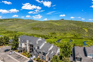 A residential area with multiple houses, a parking lot, and a hilly landscape with a river. - Park City Mountain Views • Near Canyons Village • Hot Tub, Pool, Pets (Park City)