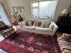 A living room with a sofa, patterned rug, and decorative items. - Cambridge Home, 100 m from bus stop to city centre, 2 km walking to city centre (Cambridge)