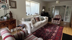 A living room with a sofa, armchair, and a patterned rug. - Cambridge Home, 100 m from bus stop to city centre, 2 km walking to city centre (Cambridge)
