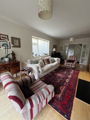 A living room with a sofa, armchair, and a patterned rug. - Cambridge Home, 100 m from bus stop to city centre, 2 km walking to city centre (Cambridge)