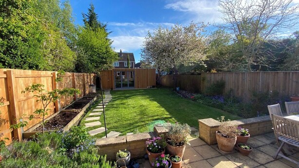 A backyard with a wooden fence, a lawn, raised garden beds, and potted plants. - Cambridge Home, 100 m from bus stop to city centre, 2 km walking to city centre (Cambridge)