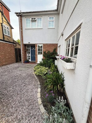 A residential building with a gravel driveway, a blue door, and a small garden with various plants. - Cambridge Home, 100 m from bus stop to city centre, 2 km walking to city centre (Cambridge)