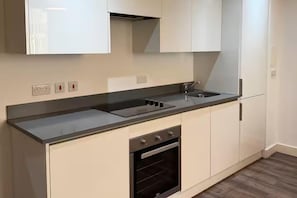 Una cuina moderna amb forn de mur, un rentapeus i una placa de cocció.