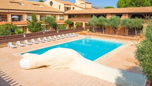 A pool area with lounge chairs and a large decorative sculpture.