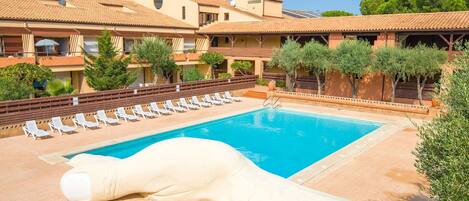 A pool area with lounge chairs and a large decorative sculpture.