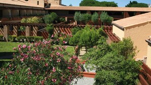 A courtyard with a pergola, potted plants, and a building with a tiled roof.