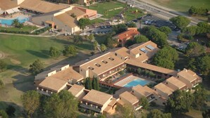 An aerial view of a resort with multiple buildings, a swimming pool, and a golf course.