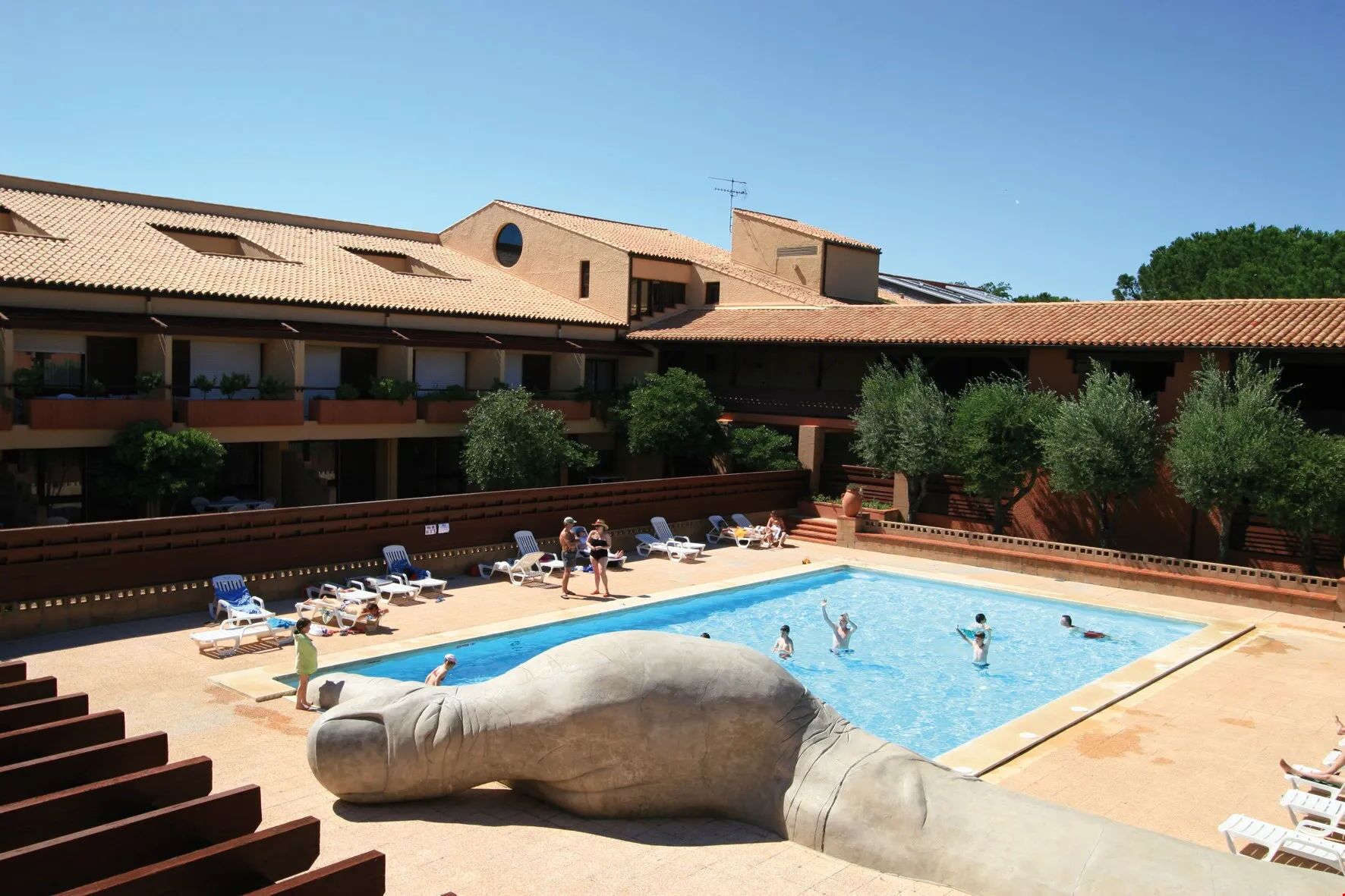 Une piscine avec des chaises longues et une grande statue.