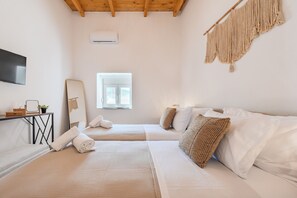 Ein Hotelzimmer mit zwei Betten, einem Fernseher, einem Spiegel und einem Fenster.