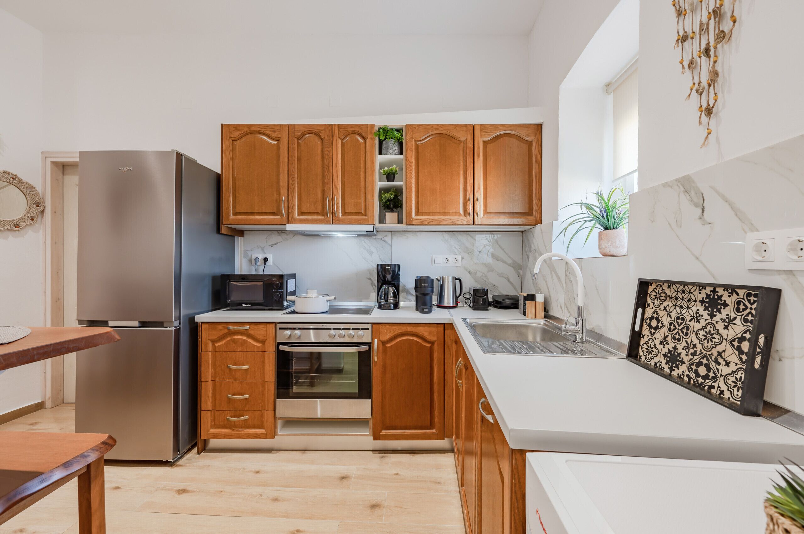 Eine moderne Küche mit Holzausstattung, Edelstahlgeräten, einer Marmor-Spritzschutzwand und einer kleinen Essecke.