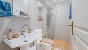 A bathroom with a sink, mirror, towel rack, shower, and toilet. - Olea Holiday House (Rethymno)