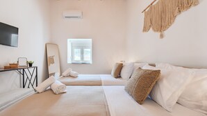 A hotel room with two beds, a TV, a mirror, and a window. - Olea Holiday House (Rethymno)