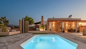 A swimming pool with a stone deck, a stone building with a patio, and a satellite dish. - Olea Holiday House (Rethymno)