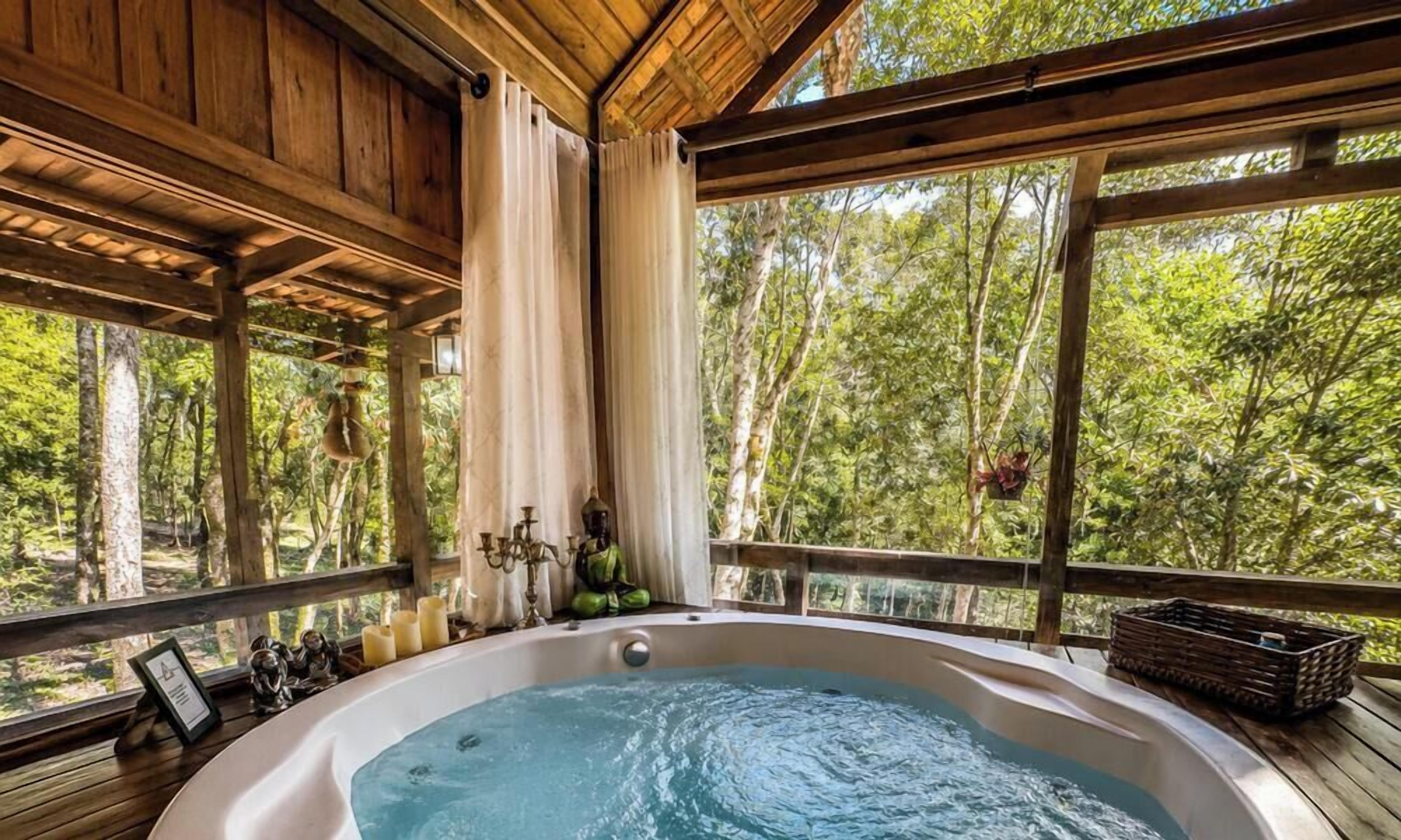 Ein Whirlpool in einer Holzhütte mit Blick auf einen Wald.