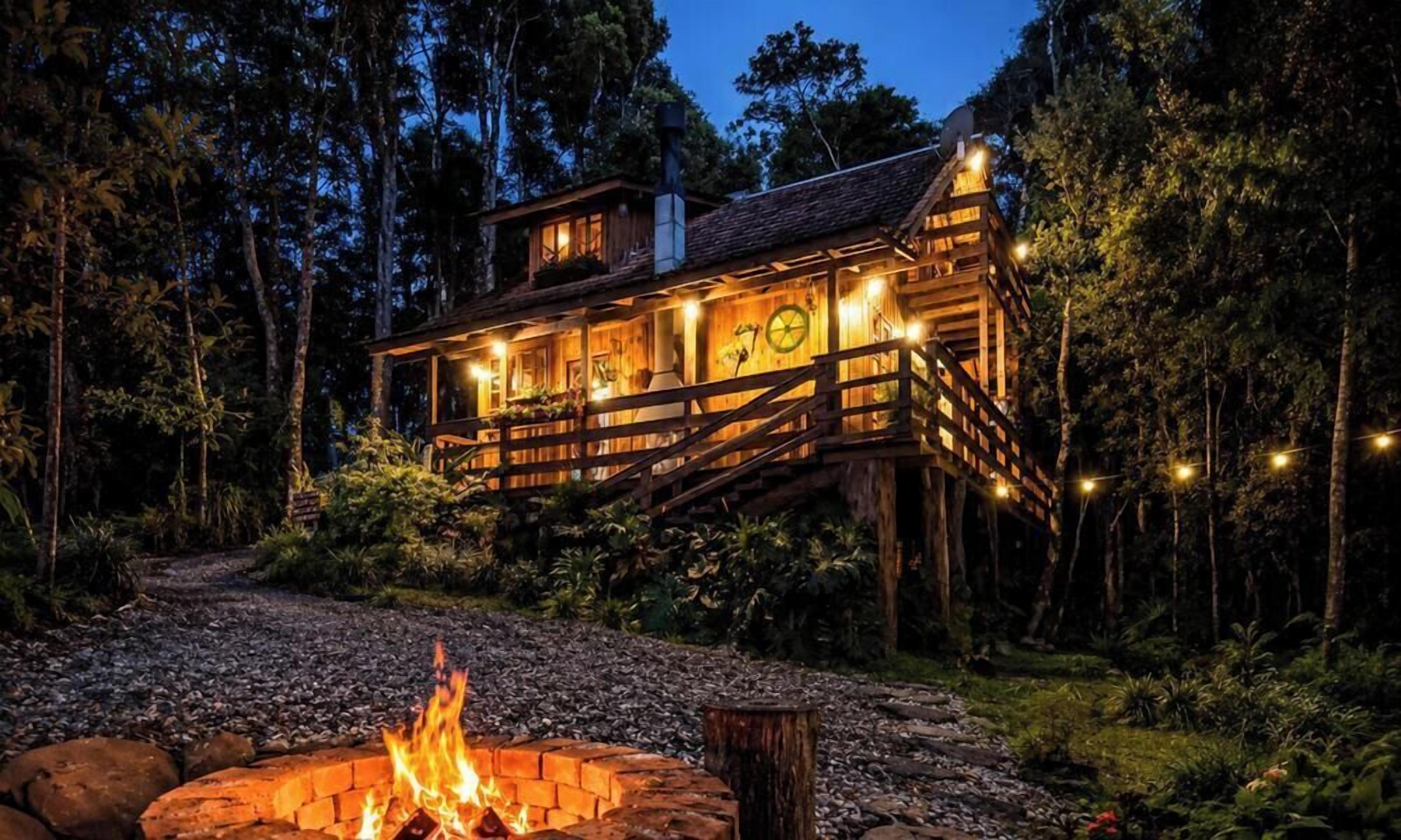 Eine Hütte mit Lagerfeuer, umgeben von einem Wald.